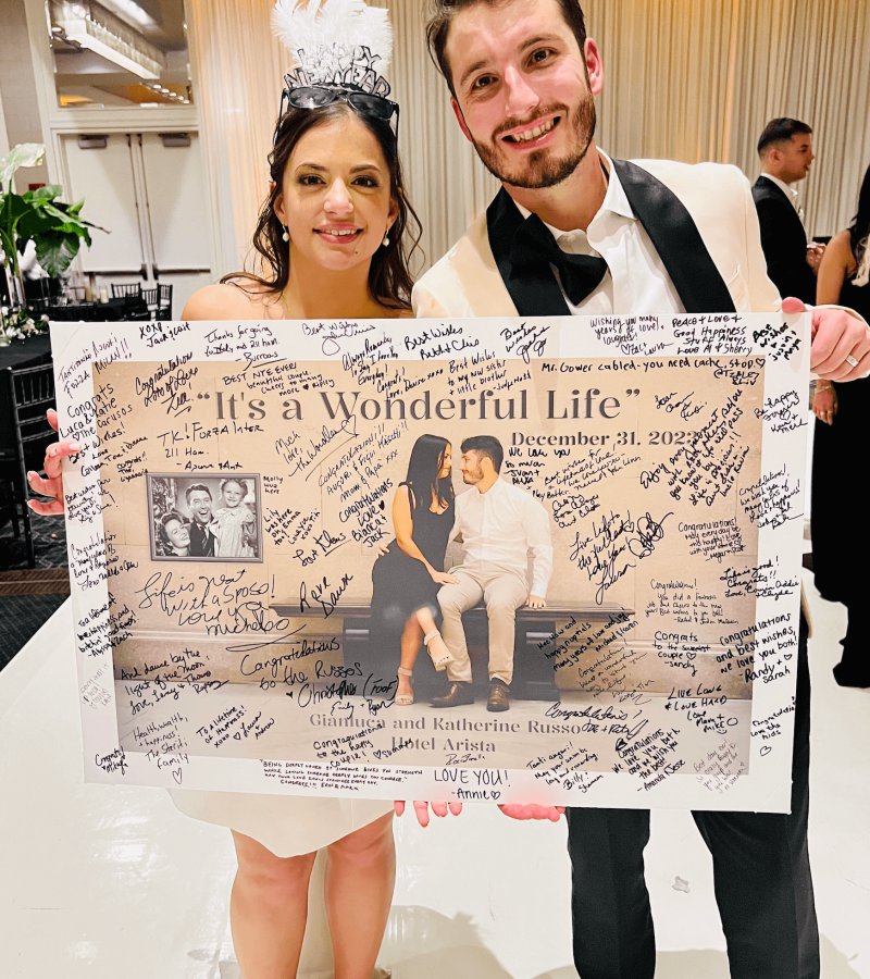 Luca and Katie holding the custom gift we made for them. Signed by all their guests